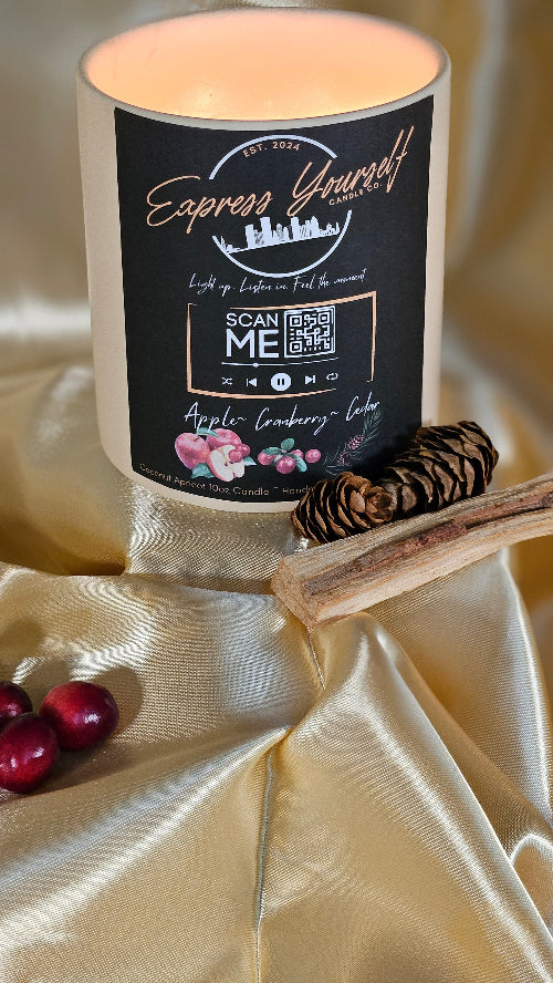 Handmade Apple Cranberry Cedar luxury coconut apricot wax candle with QR code label on gold surface.