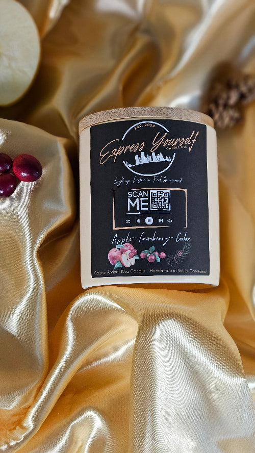 Handmade Apple Cranberry Cedar luxury coconut apricot wax candle with QR code label on gold surface.