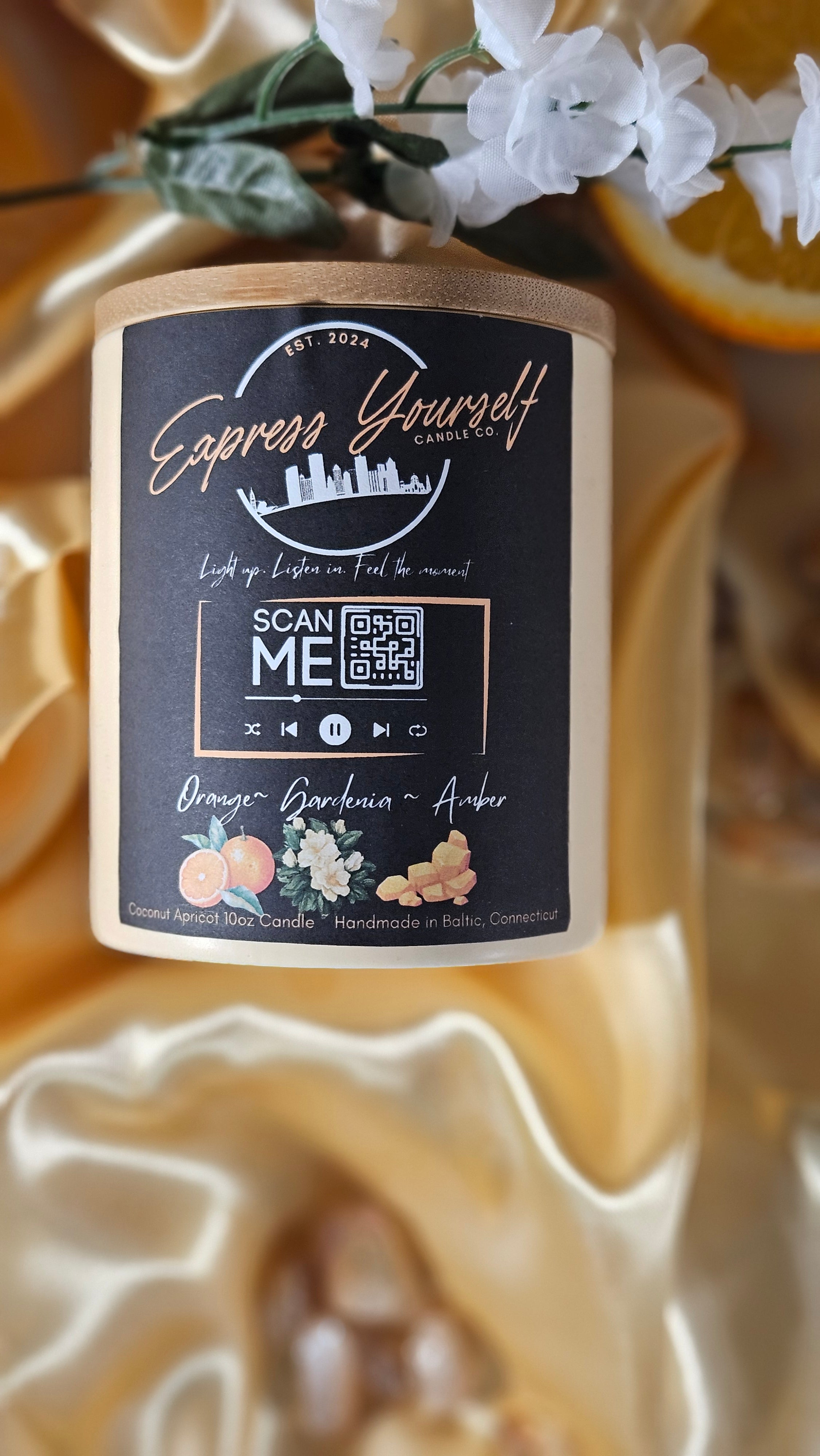 Handmade Orange, Gardenia, Amber luxury coconut apricot wax candle with QR code label on gold surface.