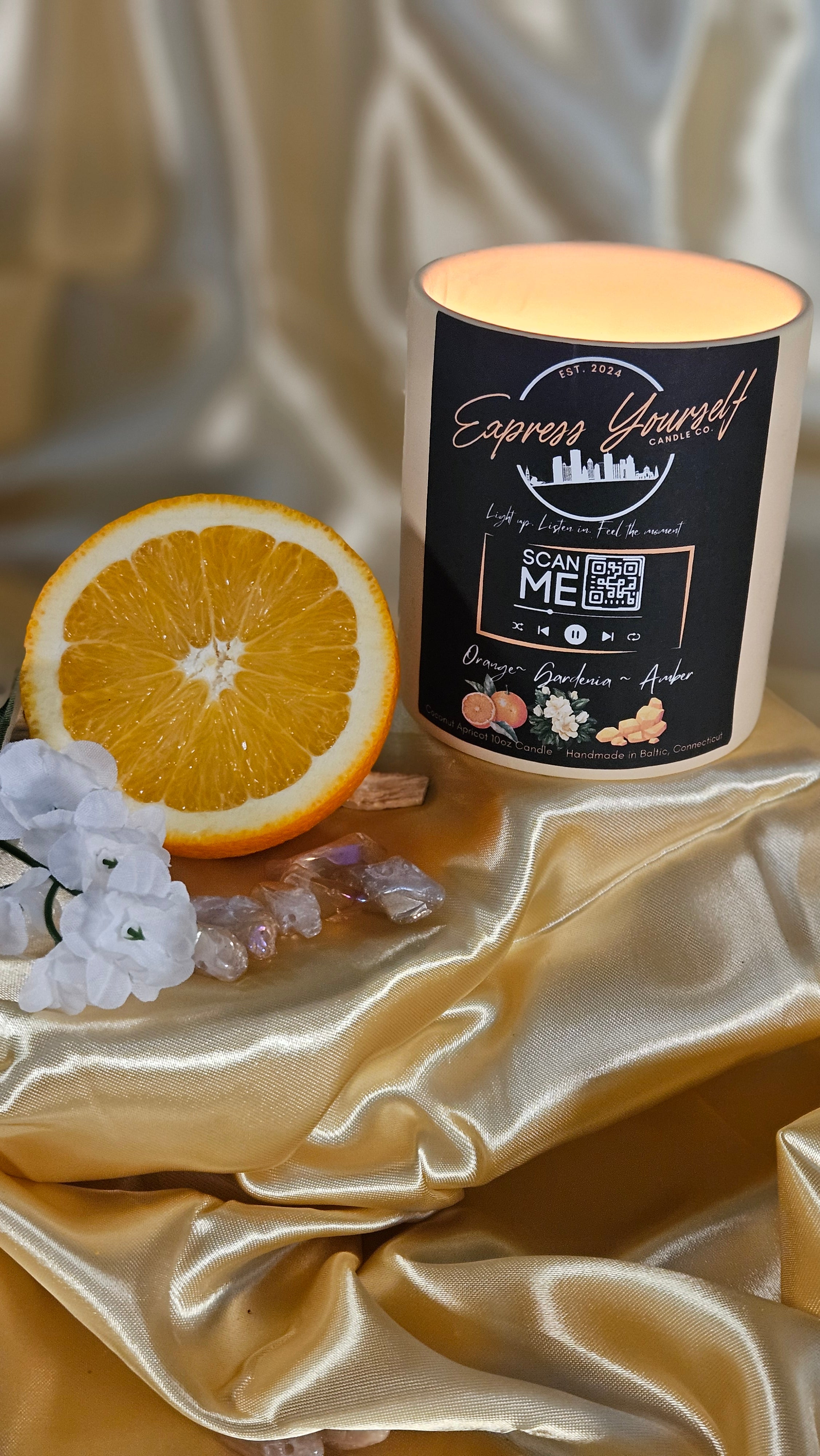 Handmade Orange, Gardenia, Amber luxury coconut apricot wax candle with QR code label on gold surface.