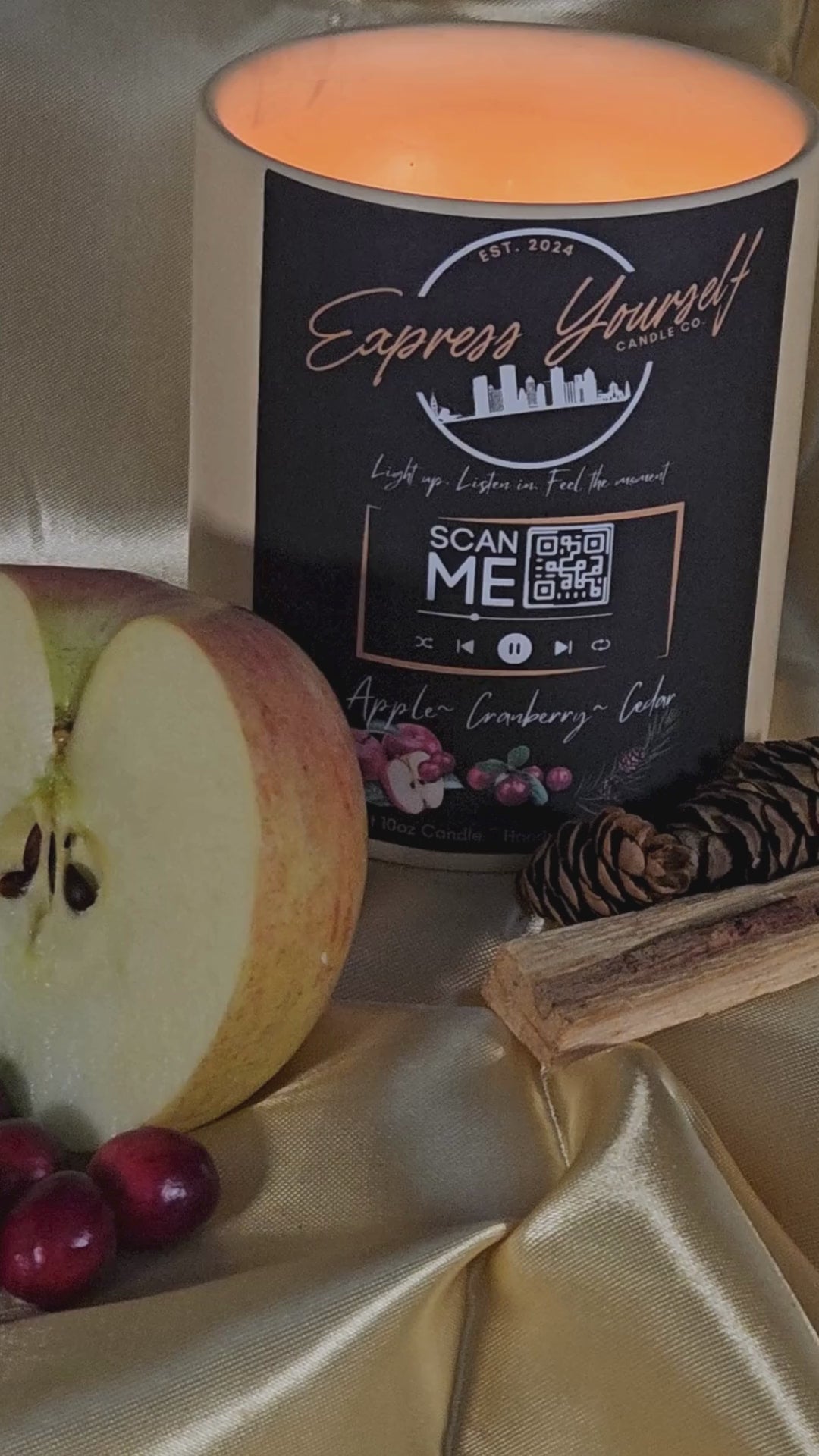 Handmade Apple Cranberry Cedar luxury coconut apricot wax candle with QR code label on gold surface.